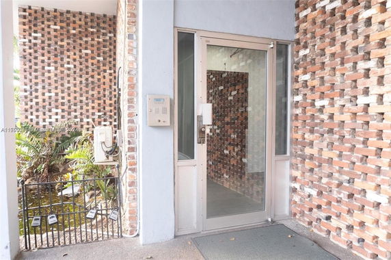 Entrance area of a building with glass door and exposed brick wall.