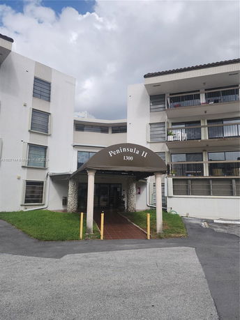 Front view of a multi-story apartment building with a covered entrance.