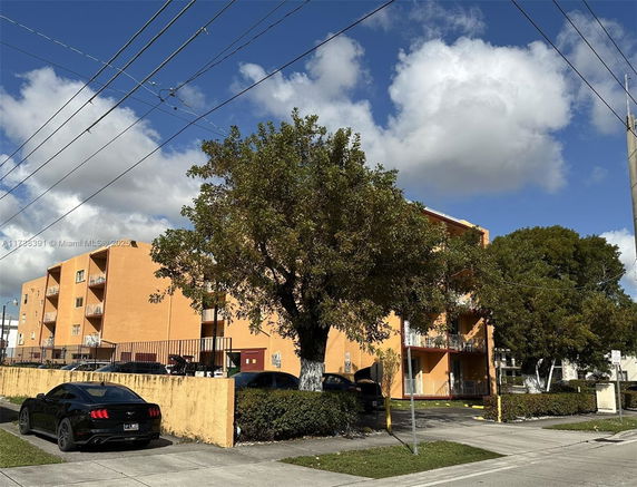 Front view of a multi-story apartment building with balconies and an orange facade.