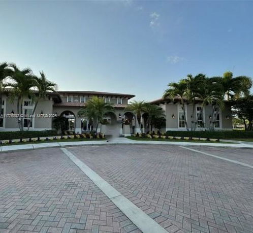 Front view of a large, two-story building with arched windows and palm trees.