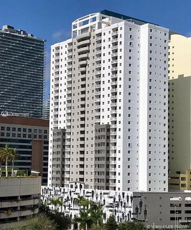 Front view of a tall residential building with multiple balconies and a modern design.