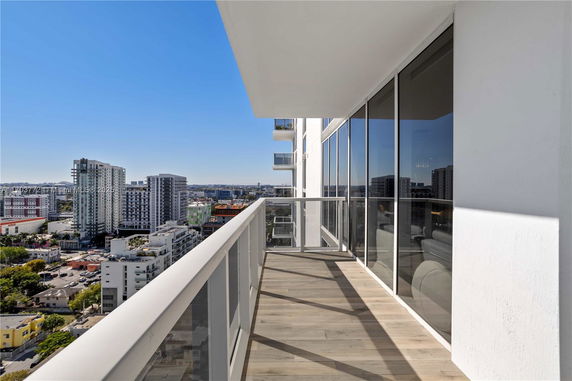 Balcony with glass railing offering a view of city buildings.