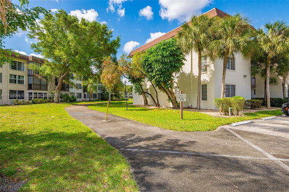 View of residential buildings surrounded by trees and grass.