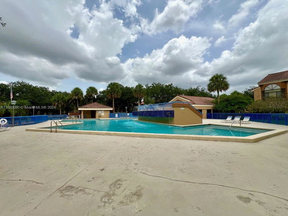 Outdoor swimming pool area with deck chairs and surrounding buildings.
