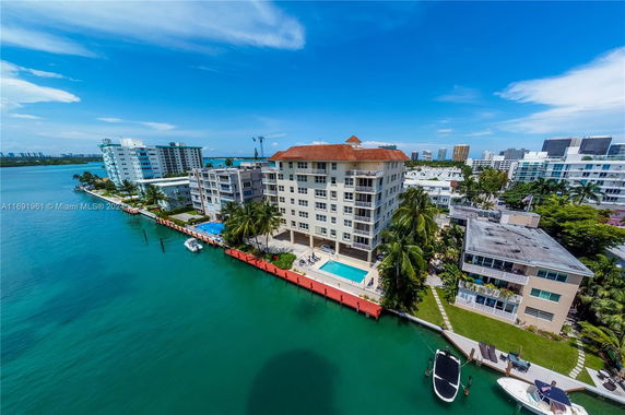Aerial view of waterfront apartment buildings with a swimming pool and dock.