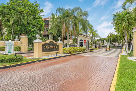 Entrance view of a residential complex with a sign reading 'San Marco' and a gatehouse.