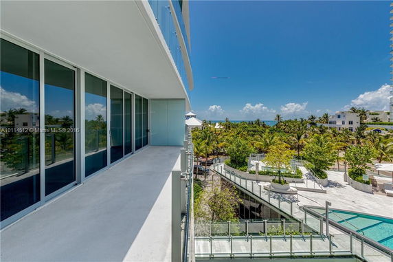 View from a building balcony overlooking surrounding areas with trees and ocean in the distance.