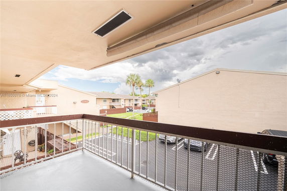 Balcony view overlooking residential complex with parking area and adjacent buildings.