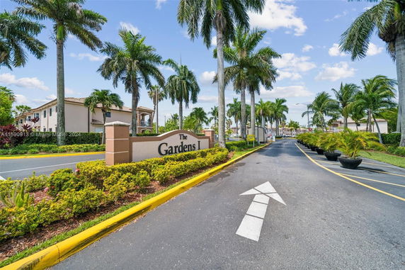 Front view of a residential complex with palm trees lining the entrance road.