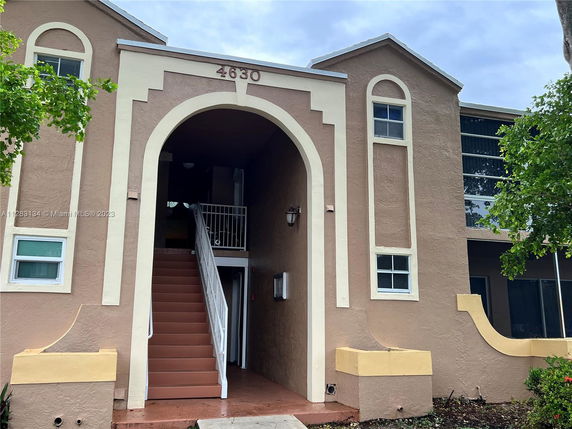 Front view of a two-story building with an arched entryway and stairs.