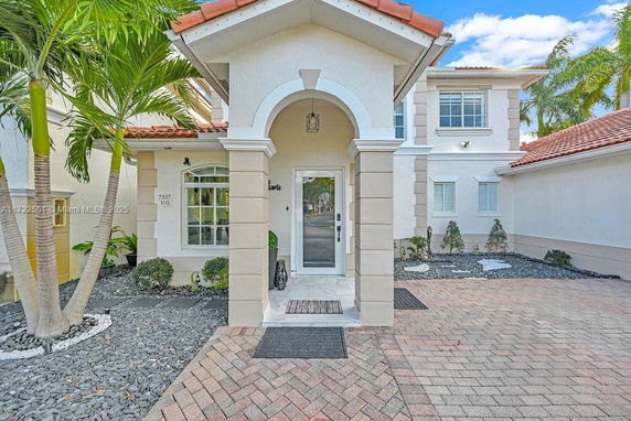 Front view of a two-story house with arched entrance and tile roof.