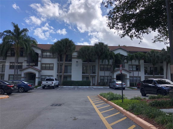 Front view of a multi-story residential building with a parking area in front.