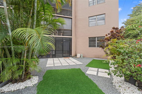Back view of a building with screened porch and garden area.