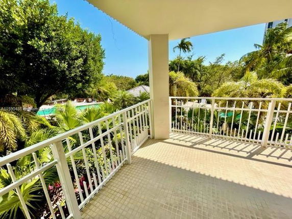 Balcony view overlooking lush greenery and a pool.
