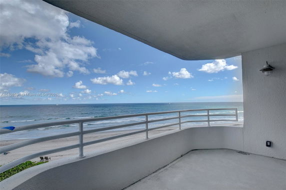 View from a building balcony overlooking the ocean with a clear sky.