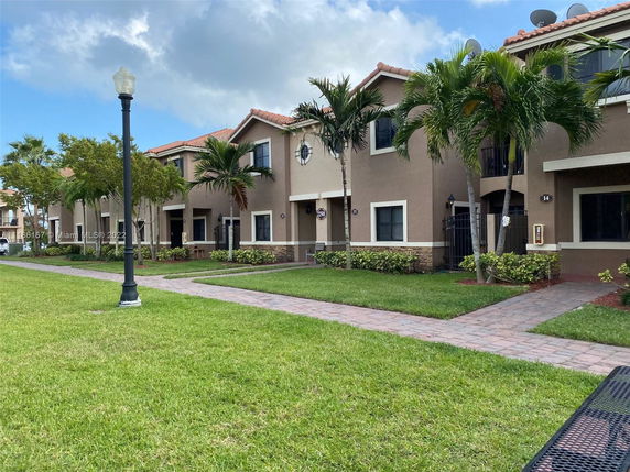 Front view of a row of two-story houses with beige exteriors and tile roofs.