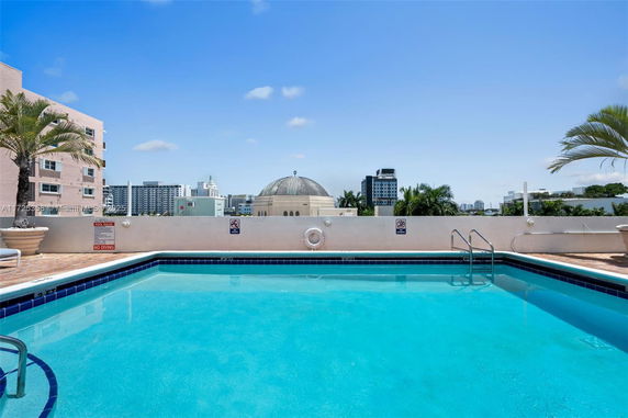 Outdoor swimming pool on a rooftop with cityscape in the background.