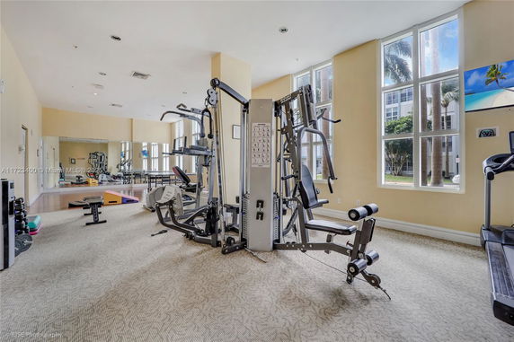 Interior of a gym with exercise equipment and large windows.