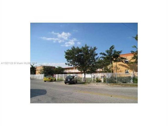 View of a multi-story building with trees and parked cars.