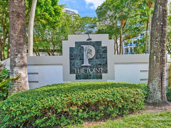 Entrance sign for The Point surrounded by trees and greenery.