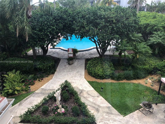 View of a swimming pool surrounded by greenery and pathway.