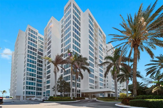 Front view of a multi-story residential building with numerous windows and a covered entrance.