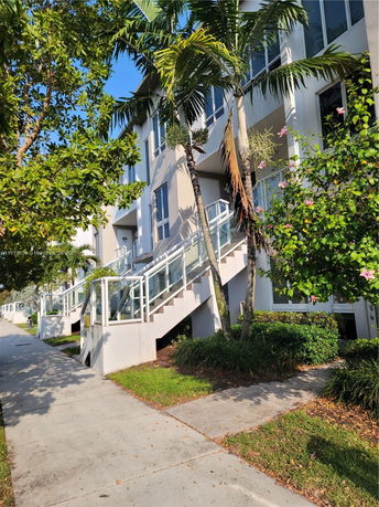 Front view of a modern multi-story building with large glass windows and staircase entry.
