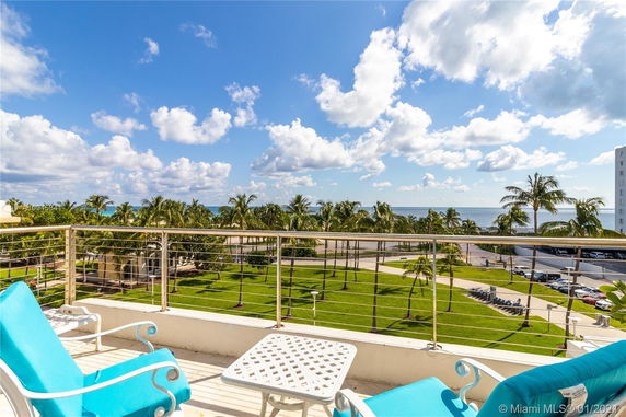 View from a balcony overlooking palm trees and the ocean.