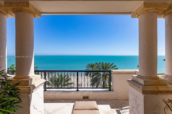 Panoramic view of the ocean from a building balcony with classical columns and railings.
