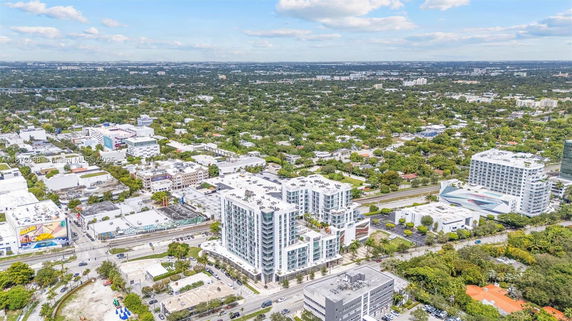 Aerial view of a cityscape with multiple buildings and green areas.