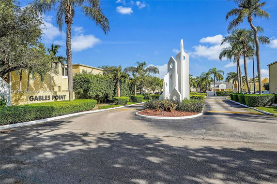 Front view of a residential entrance with a modern sculpture and palm trees.