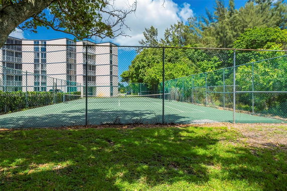 Tennis court adjacent to a multi-story residential building.