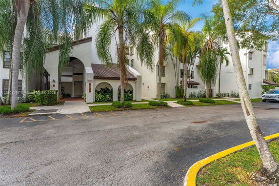 Front view of a multi-story building with archway entrance and palm trees.