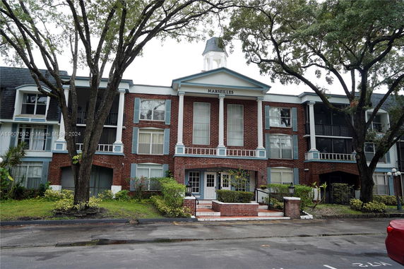 Front view of a multi-story brick building with white columns and windows.