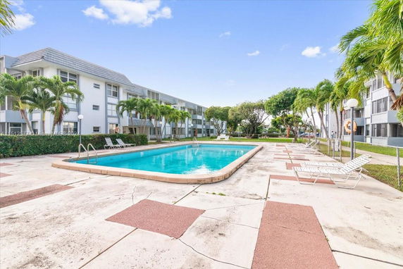 Swimming pool area adjacent to a multi-story residential building.