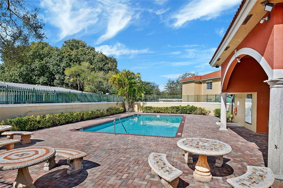 Outdoor swimming pool area with surrounding brick patio and seating.