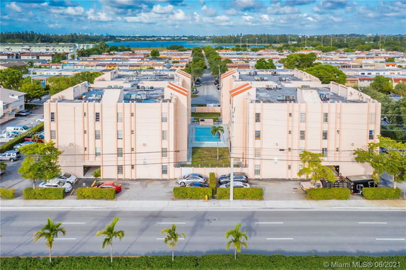 Front view of a multi-story apartment complex with a central courtyard and swimming pool.