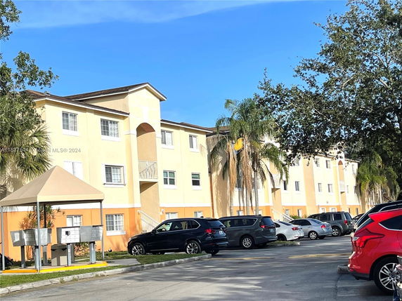 Front view of a multi-story apartment building with a parking area.