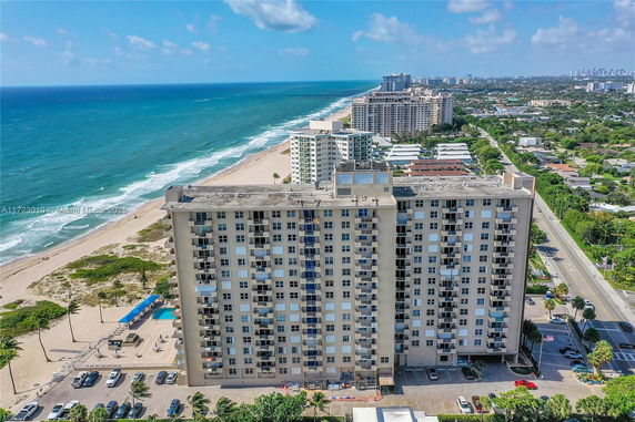 High-rise building near the coastline with ocean and surrounding cityscape.