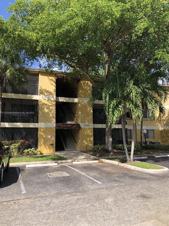Front view of a three-story apartment building with a yellow facade and balconies.
