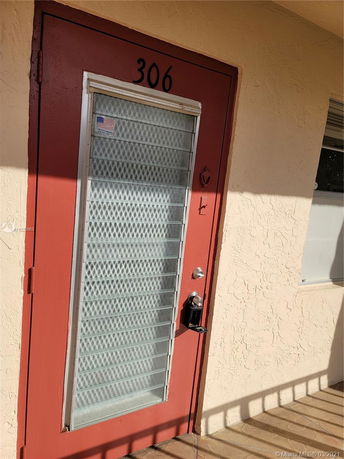 Red door with the number 306 on a stucco building facade.