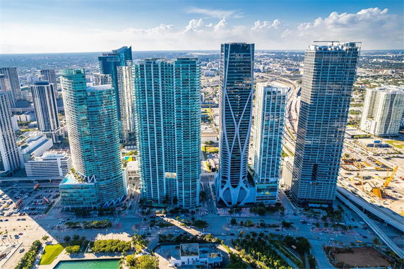 Aerial view of a cityscape with several modern skyscrapers of varying heights and designs.