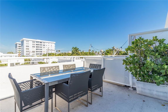Rooftop area with outdoor seating and potted plants under a clear blue sky.