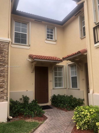 Front view of a two-story building with tan exterior and tile roof accents.