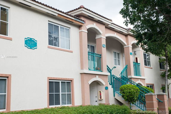 Front view of a two-story building with teal railings and archways.