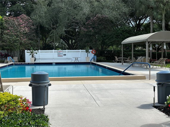 Outdoor swimming pool area with lounge chairs and umbrella.