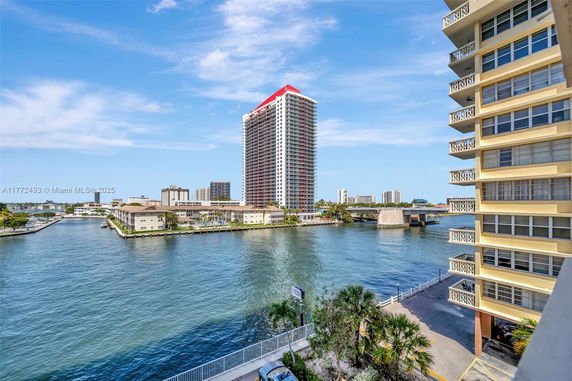 Panoramic view of buildings near a waterfront with a high-rise structure in the distance.