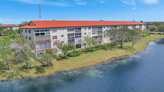 Rear view of an apartment building with a red roof by a water body.