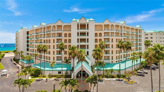 Front view of a multi-story residential building with teal-colored roofs and balconies.