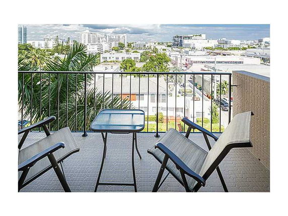 View from balcony overlooking cityscape with chairs and table in the foreground.